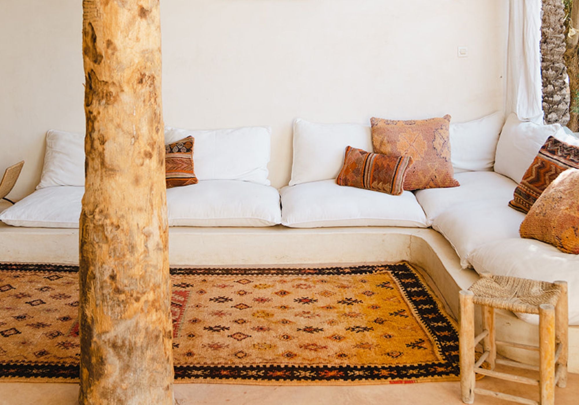 Vintage Moroccan rugs and cushions on the ground in front of a couch in Marrakech Morocco - Nouvelle Nomad Studio