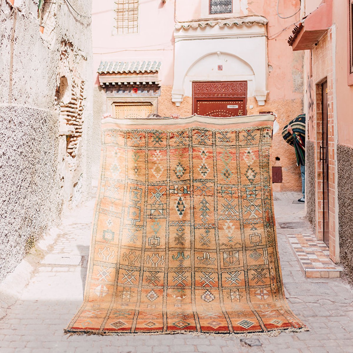 A Zemmour vintage Moroccan rugs being held up in the street in Marrakech, Morocco - Nouvelle Nomad