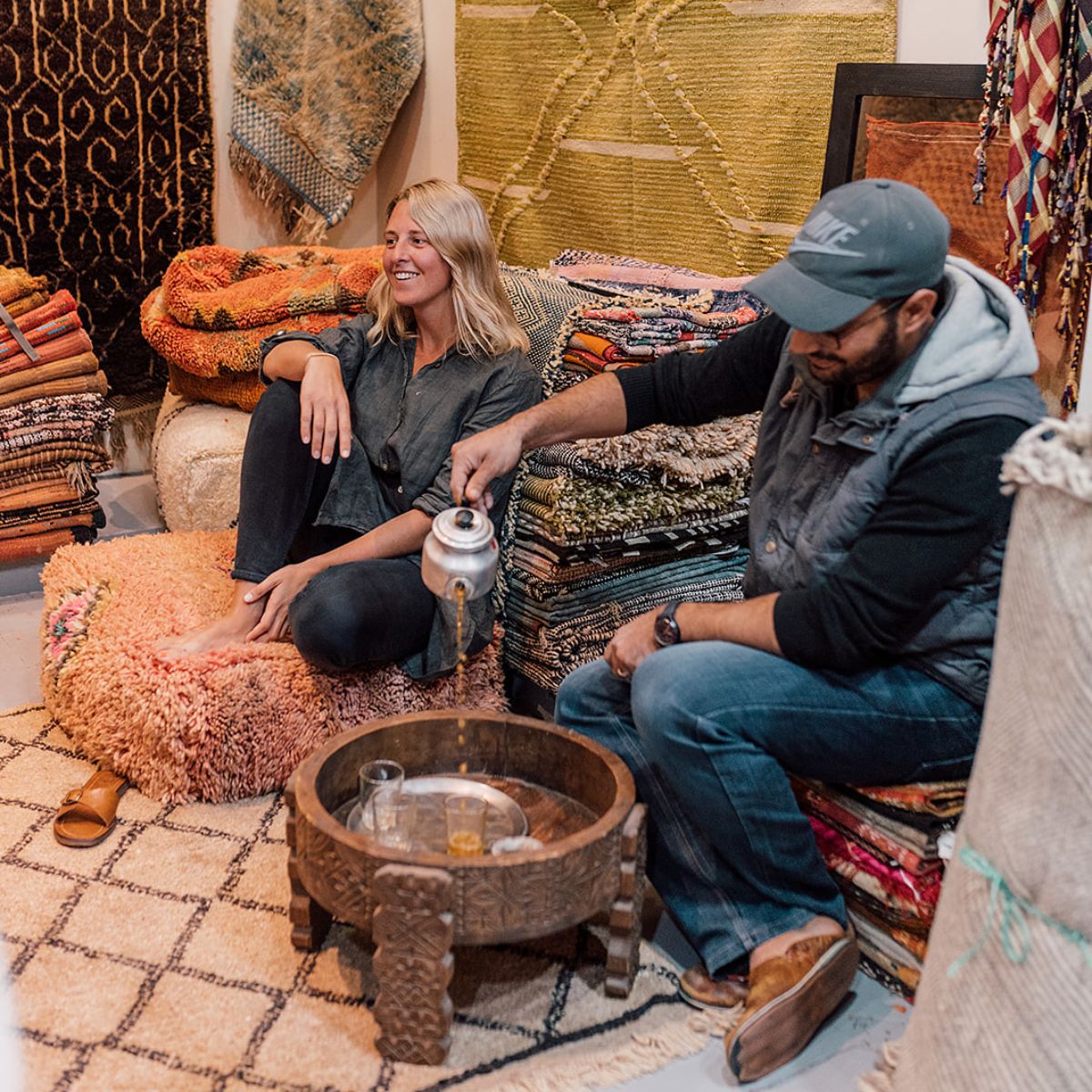 Bridget and Soufiane drinking mint tea on a stack of rugs and cushions in Marrakech