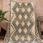 A marmoucha style vintage Beni Ourain rug being held up - Nouvelle Nomad
