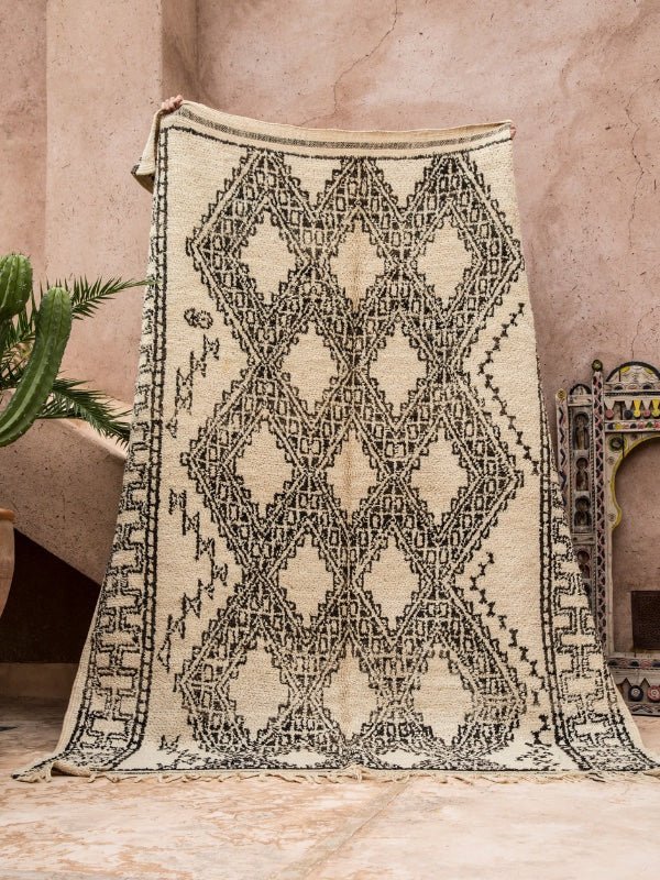 A marmoucha style vintage Beni Ourain rug being held up - Nouvelle Nomad