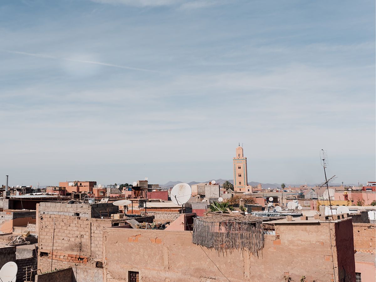 The Marrakech medina skyline showing pink buildings and mosque with blue sky and the Atlas Mountains in the background