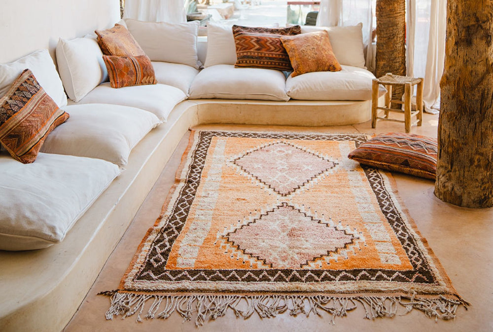 A terracotta coloured vintage Moroccan rug in front of a white couch | Nouvelle Nomad